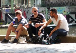 Three friends gather along Canal St. Martin to chat and discuss their weekend plans.